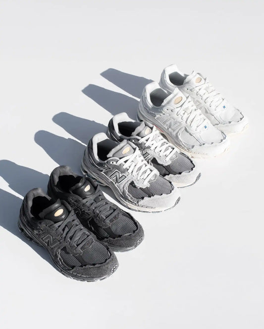 Black and white new balance sneakers with textured leather uppers, mesh accents, and gold hardware.