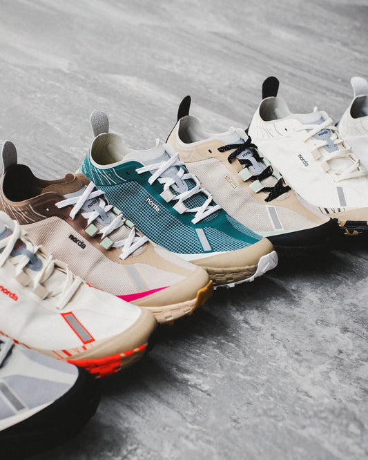 A pair of nordskog trail running shoes in a beige and teal colorway with mesh uppers, white laces, and contrasting black accents on the heel tab.