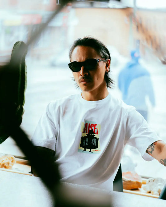 White aise t-shirt with a black and red graphic print featuring a cartoon character.