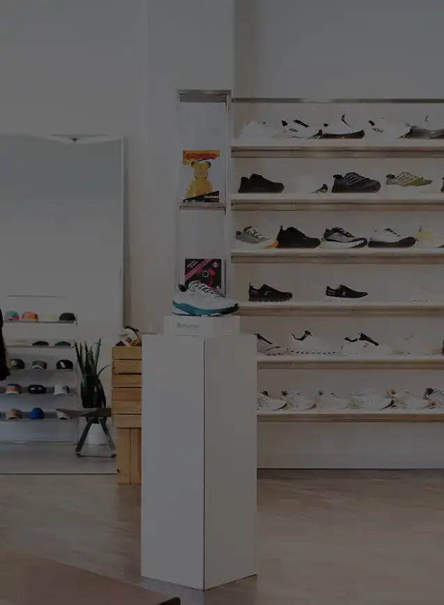 White pedestal display stand with black and silver accents, designed for showcasing shoes.